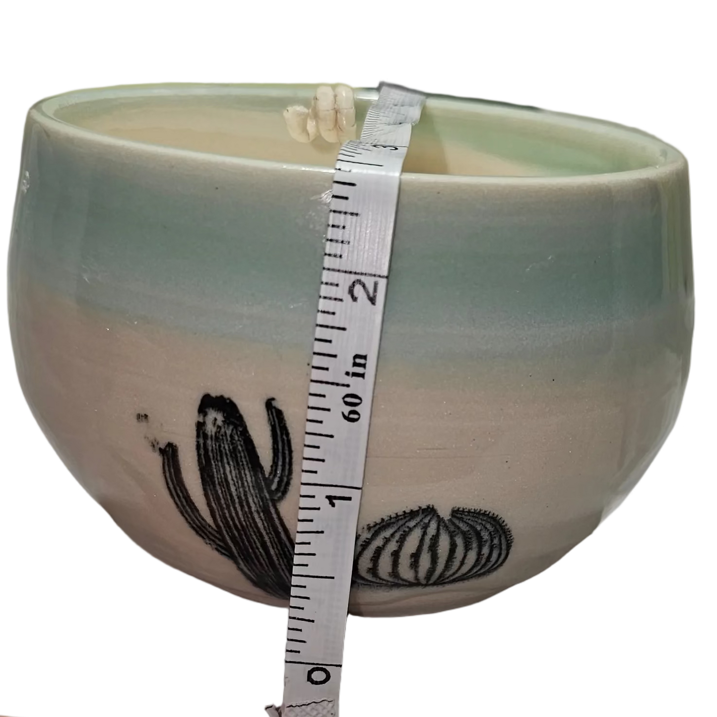 Ceramic bowl with a measuring tape for scale on a white surface, soy candle