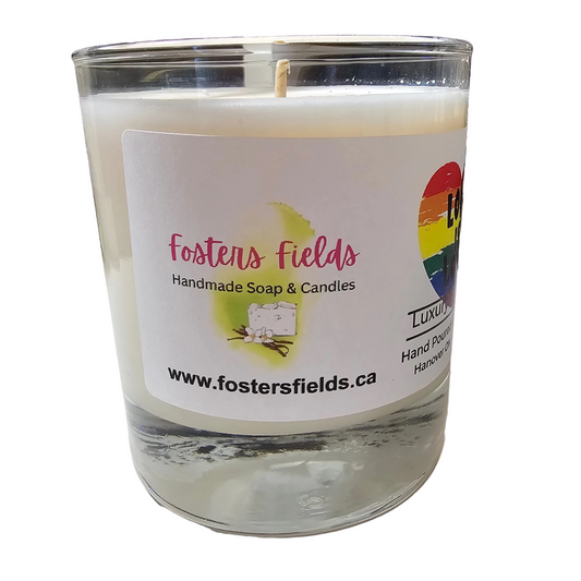 Candle in a glass jar with a 'Fosters Fields' label on a white surface.