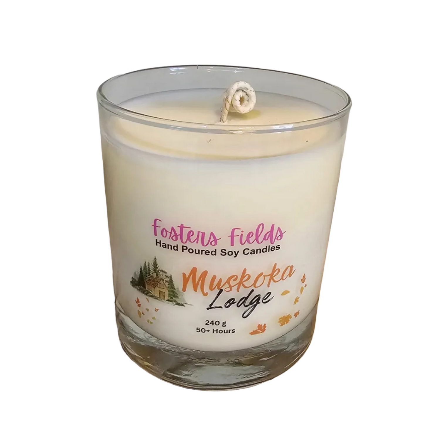 A hand-poured soy candle in a clear glass jar with a white wax fill and a single wick. The label reads 'Fosters Fields Hand Poured Soy Candles' and 'Muskoka Lodge'.