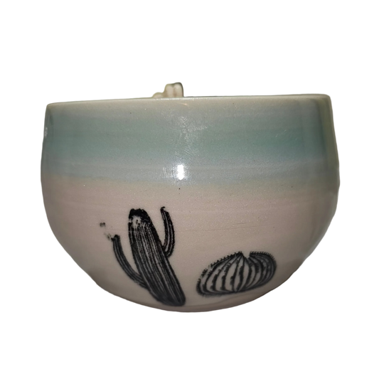 Ceramic bowl with a cactus design on a white surface, made into a soy candle