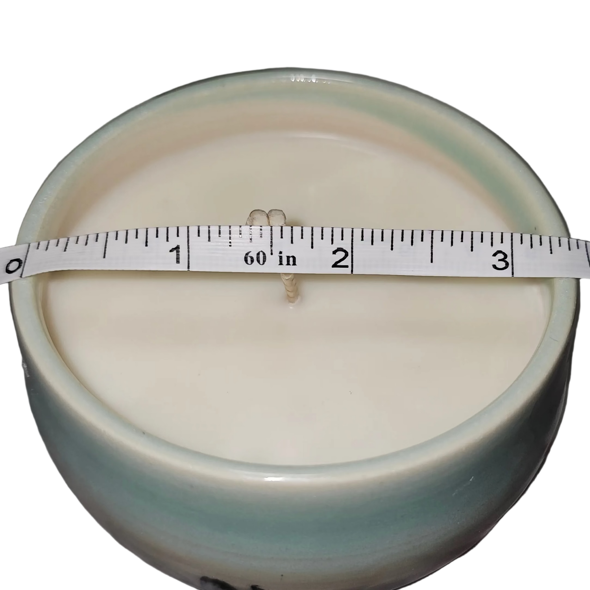 Ceramic container with a measuring tape on top, placed on a textured surface. Soy Candle