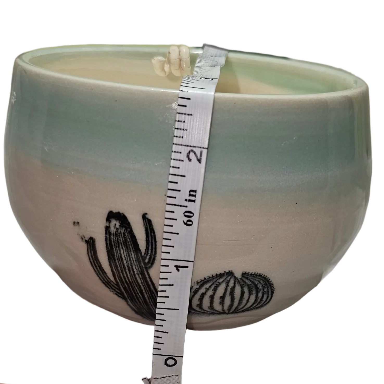 Ceramic bowl with a measuring tape for scale on a white surface, soy candle