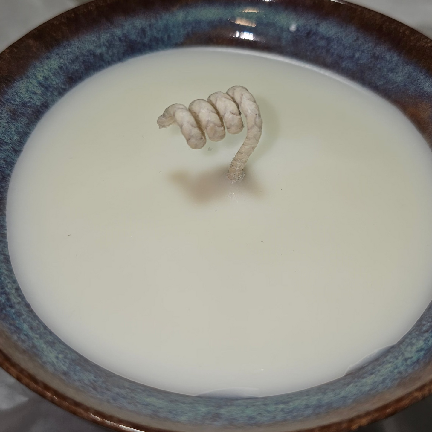 pottery bowl with shades of blue, red and pink. filled with soy wax