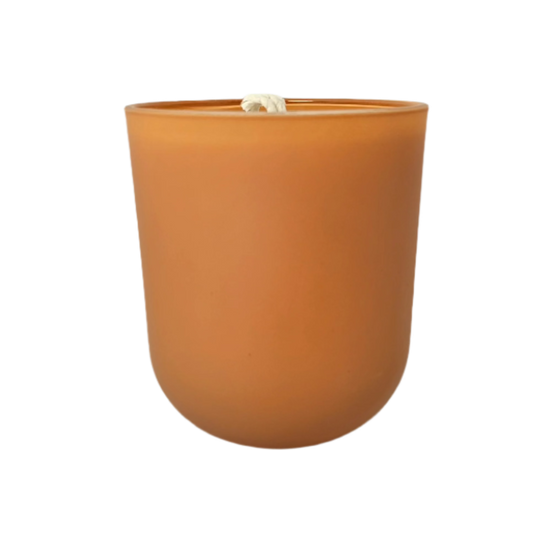 Artisan soy candle with citrus scent, hand-poured into an orange glass jar

