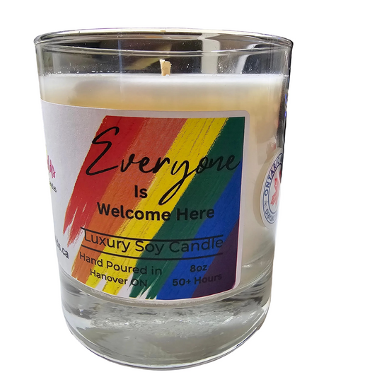Candle in a glass jar with a rainbow pride label on a white surface