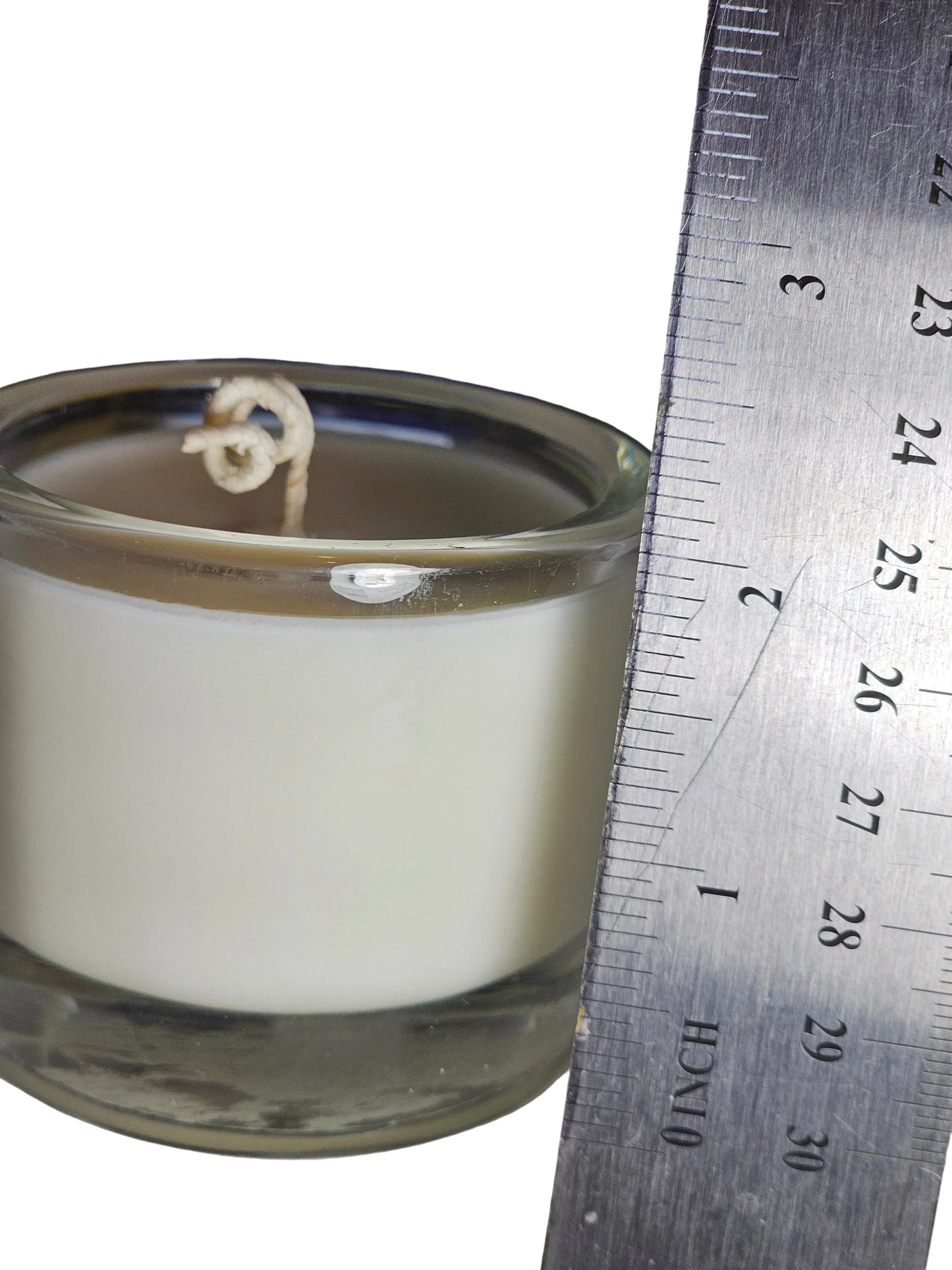 soy candle in glass vessel with a ruler measuring the height