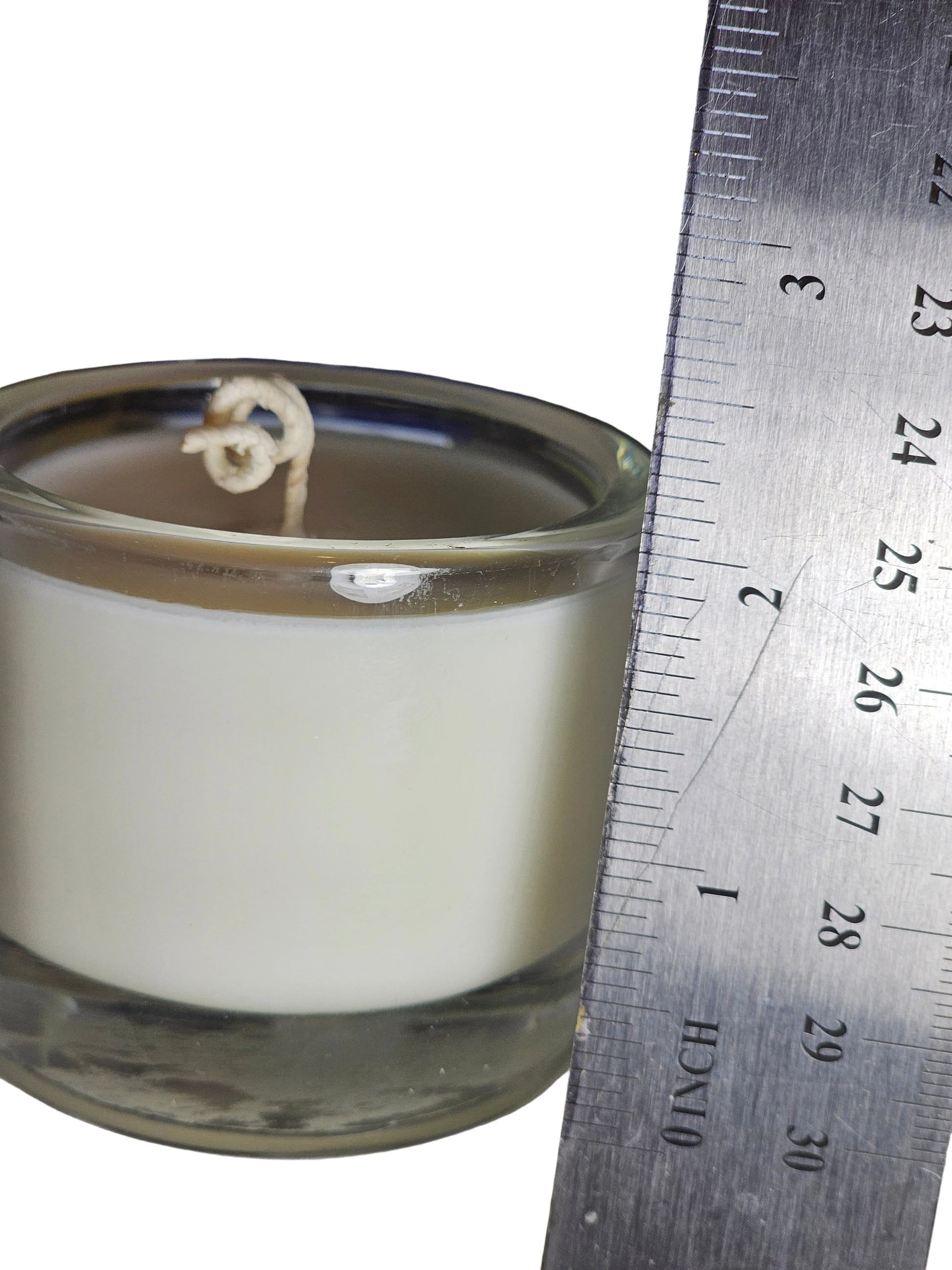 soy candle in glass vessel with a ruler measuring the height